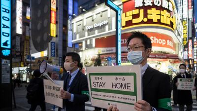 Staff members of the Tokyo metropolitan government hold signs as they call for people to stay home in 2020
