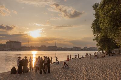 People enjoy the warm weather next to the Dnipro River on Trukhaniv Island, in Kyiv, last month. Getty Images