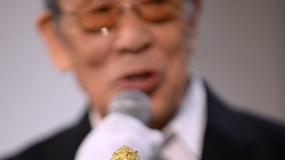 Japanese actor Haruo Nakajima speaks behind the 24-cm-tall and 15-kilogram gold statue of Godzilla unveiled during a press preview of the Godzilla exhibition in Tokyo on July 19, 2014. The Godzilla statue will take orders starting on July 20 at the Ginza Tanaka jewellery shop with a price of 150 million yen (about Dh5.43 million). Toshifumi Kitamura / AFP photo