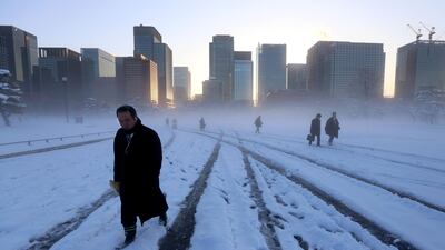 Morning commuters walk across a snow-covered field on the grounds of the Imperial Palace as buildings stand in the business district in Tokyo on Tuesday, Jan. 23, 2018. Takaaki Iwabu / Bloomberg