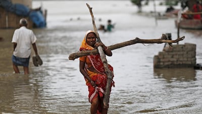 A woman wades through a flooded street carrying logs of wood to be used to reinforce her shanty submerged in a slum area after a rise in the waters of the river Yamuna in New Delhi, India. Adnan Abidi/Reuters