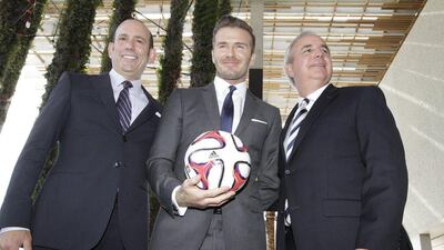 Former England and Manchester United star, David Beckham, centre, poses for photos after holding a news conference at the Perez Art Museum Miami, in Miami, Florida on Wednesday. Beckham said he will buy a US team to play Major League Soccer and bring it to Miami, confirming the worst-kept secret in world football. Major League Soccer Commissioner Don Garber, left, and and Miami-Dade County Mayor Carlos A. Gimenez joined Beckham at the news confernece. AFP PHOTO / Alexia FODERE