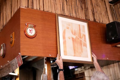 Grant McCreadie, vice commodore, adjusts the photo of the late Sheikh Saqr bin Mohammed opening Raksa in the 1970s. Reem Mohammed / The National