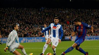 Luis Suarez scores a goal against Espanyol goalkeeper Diego Lopez. Albert Gea / Reuters