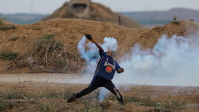 A Palestinian protester throws back an Israeli tear gas canister on the eastern border of the Gaza Strip. EPA