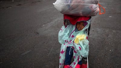 A migrant child departs a shelter during rainfall. Reuters