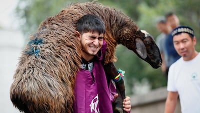 A man squats as he carries a sheep during a competition to mark Eid Al Adha at the Central Mosque in Almaty, Kazakhstan. Reuters