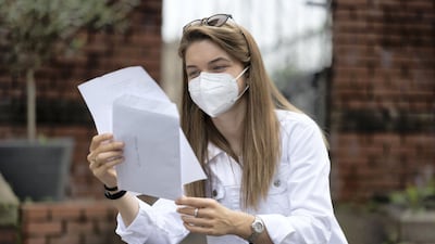 A student wears a surgical mask while looking at her A Level results at Ffynone House School in Swansea, Wales.