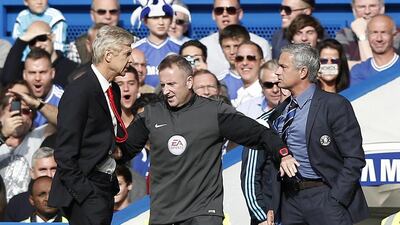 Chelsea manager Jose Mourinho, right, and Arsenal manager Arsene Wenger are kept apart by the fourth official Jonathan Moss during the Premier League match at Stamford Bridge in London on October 5, 2014. Adrian Dennis / AFP