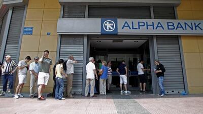People wait in a queue to withdraw money from an ATM outside a branch of Greece’s Alpha Bank in Athens. Alexandros Vlachos / EPA