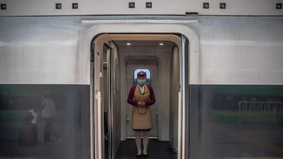 A train attendant wearing a protective face mask stands on a train to Wuhan, at the railway station in Beijing, China. EPA