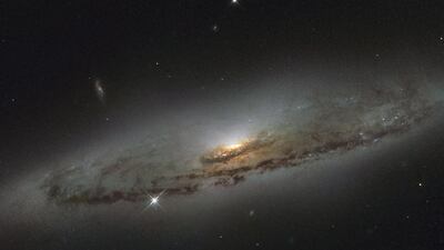 Spiral galaxy NGC 4845, 65 million light years away in the Virgo constellation, captured by the Hubble Space Telescope in January. The dust-mottled disc around the glowing centre signifies a black hole. NASA / Reuters