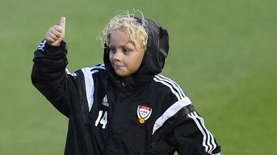 A young fan gives his approval while shielding himself from the rain in a UAE tracksuit.