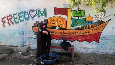 A Palestinian woman, who fled her home due to Israeli air and artillery strikes, washes clothes at a UN-run school where she takes refuge, in Gaza City, May 18. Reuters