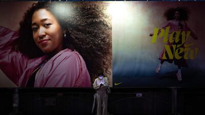 A woman looking at her mobile phone in Tokyo's Shibuya district, as lights of commercial buildings are turned off after 8pm to prevent attracting crowds amid a coronavirus state of emergency. AFP