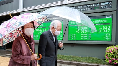 A couple pass an electronic stock board of a securities company in Tokyo. Asian stock markets rose on Wednesday after Wall Street hit a high following an uptick in US inflation and an order by regulators to suspend use of Johnson & Johnson's coronavirus vaccine. AP Photo