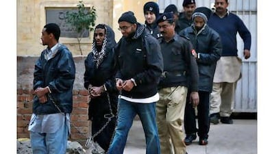 A Pakistani policeman escorts hand-cuffed men identified as Aman Hassan Yemer, left, Ahmed Abdulah Minni, second left, Waqar Hussain Khan, right, Ramy Zamzam, back left, and Umar Farooq, back right, as they leave a police station after their court appearance in Sargodha, Punjab province, on January 4, 2010.