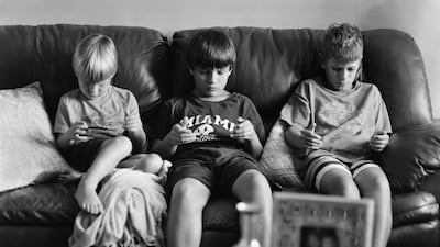 Three children sit on a couch, concentrating intently on the space between their iPad-less hands. By removing the tablets from their hands, Pickersgill highlights just how enveloped we have become by the contents of our screens. Courtesy Eric Pickersgill