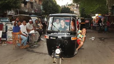 Boys drive a three-wheeled motor rickshaw, or tuk-tuk, in the blighted Cairo suburb of Imbaba.