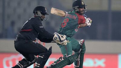 Bangladesh's Mohammad Mithun, right, plays a shot as the UAE wicketkeeper Swapnil Patil looks on during their Asia Cup T20 cricket match at the Sher-e-Bangla National Cricket Stadium in Dhaka on February 26, 2016. AFP PHOTO/Munir uz ZAMAN