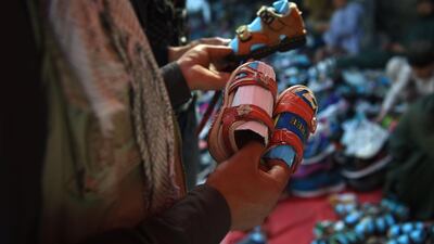 An Afghan man looks at sandals for children ahead of Eid Al Fitr, at a roadside in Kabul. AFP
