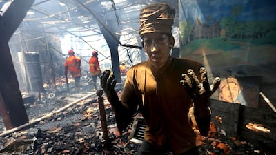 A scorched statue sists in the ashes as a fireman tries to extinguish parts of a huge fire that spread through the Maritime Museum in Jakarta, Indonesia. Tatan Syuflana / AP Photo