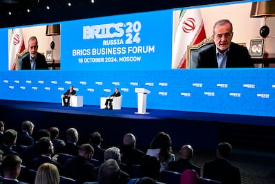 Russian President Vladimir Putin listens as Iranian President Masoud Pezeshkian addresses participants on screen during the Brics Business Forum in Moscow on Friday. AP