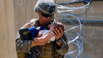 A US Marine comforts an infant while they wait for the mother during an evacuation at Hamid Karzai International Airport, in Kabul, Afghanistan, August 21. EPA/US Marine Corps