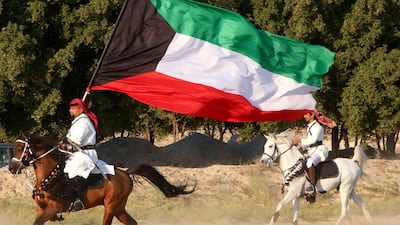 A Kuwaiti man holds a national flag as he rides a horse in Kuwait City during celebrations to mark the country's 60th National Day and the 30th anniversary of its liberation from Iraqi occupation. AFP