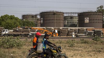 A motorcyclist rides past an oil depot in New Delhi. India's heavy dependence on commodity imports such oil, combined with elevated prices, are contributing to the country's widening trade deficit. Bloomberg