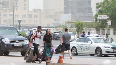 Tourists in one of the hotels in Dubai Marina with their luggage try to find a cab as police block the area around the burning building. Leslie Pableo for The National
