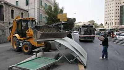 A large tractor removes a bus station which was destroyed in a deadly bulldozer rampage driven by a Palestinian man yesterday in Jerusalem's busy Jaffa Road.
