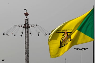 A flag of Iraq's pro-Iran paramilitary group Kataib Hezbollah flutters against the backdrop of a swing ride at an amusement park in Baghdad. AFP
