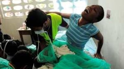 Dr Mootaz Ali, part of a Qatari team, performs surgery on a girl's broken leg in a makeshift surgery in a classroom in Port-au-Prince.