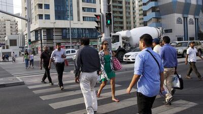 People walk across the intersection of Sheikh Zayed Bin Sultan and Hamdan Bin Mohammed streets in Abu Dhabi. Christopher Pike / The National