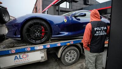 A police officer looks on as a luxury vehicle is seized on the outskirts of Bucharest, in the case against Tate. AP