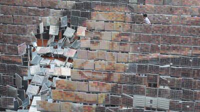 A student tries to keep boards dry during rain on a mosaic portrait of the Queen Mother Sirikit in Bangkok, Thailand. AP