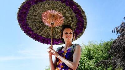 A model wearing a dress and carrying an umbrella made from orchids poses in the M&G garden. EPA