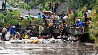 Residents clear debris stuck by a bridge. AFP