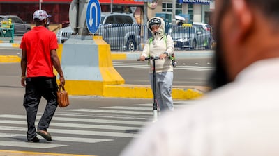 An e-scooter and a pedestrian cross Zayed The First Street in central Abu Dhabi. Victor Besa / The National
