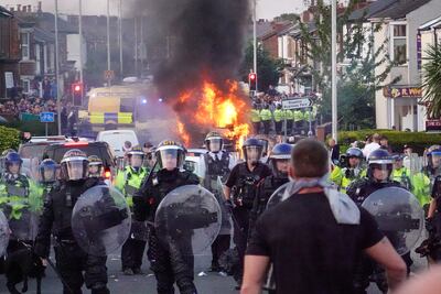 Riot police hold back protesters near a burning police vehicle after disorder broke out in 2024 in Southport. Getty Images