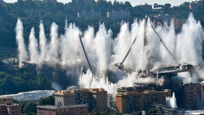 A cloud of dust rises as the remaining spans of the Morandi bridge are demolished in a planned expolosion, in Genoa, Italy. AP