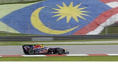 Mark Webber passes the flag of Malaysia on his way to a second-place finish in Sepang.