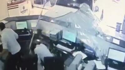 Staff race for cover as the car smashes through the window.