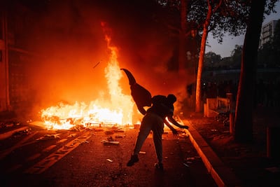 A protester throws material into a fire along a canal in Paris. AFP
