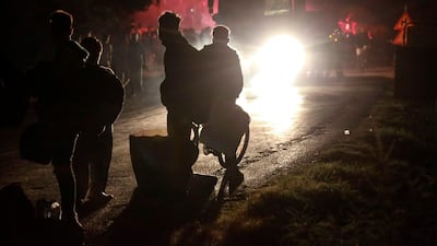 Refugees stand with their belongings after being evacuated as a fire burns in the Moria camp on the island of Lesbos. AFP