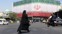 A veiled Iranian woman walks past a billboard featuring Iran's national flag at Enqelab Square in Tehran, Iran, 14 June 2026. US President Donald Trump saying on a social media platform that a deal could be signed soon. EPA/ABEDIN TAHERKENAREH RESTRICTIONS: NO Access Israel Media/Persian Language TV Stations Outside Iran/Strictly No Access BBC Persian/VOA Persian/Manoto TV/Iran International TV. (As mandated by Iran's Directorate General for Foreign Media) --