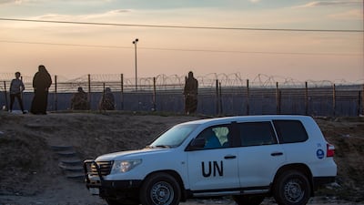 An UNRWA vehicle drives past displaced Palestinians walking near the Egyptian border in Rafah. EPA