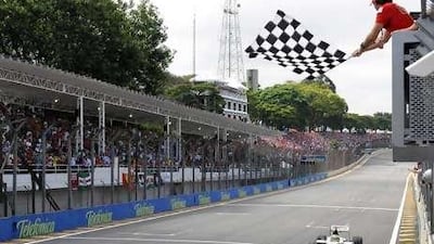 Felipe Massa waves the checkered flag as Jenson Button goes past the end of the Brazilian GP at Interlagos last year.