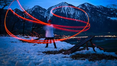 A long exposure image shows the motion of a glowing wooden disc as it is hurled towards the valley as part of the scheibenschlagen tradition in the village of Untervaz, Switzerland. EPA